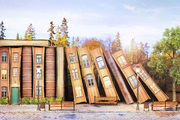 Holzhäuser in Buchform stehen aneinandergereiht vor einem Wald